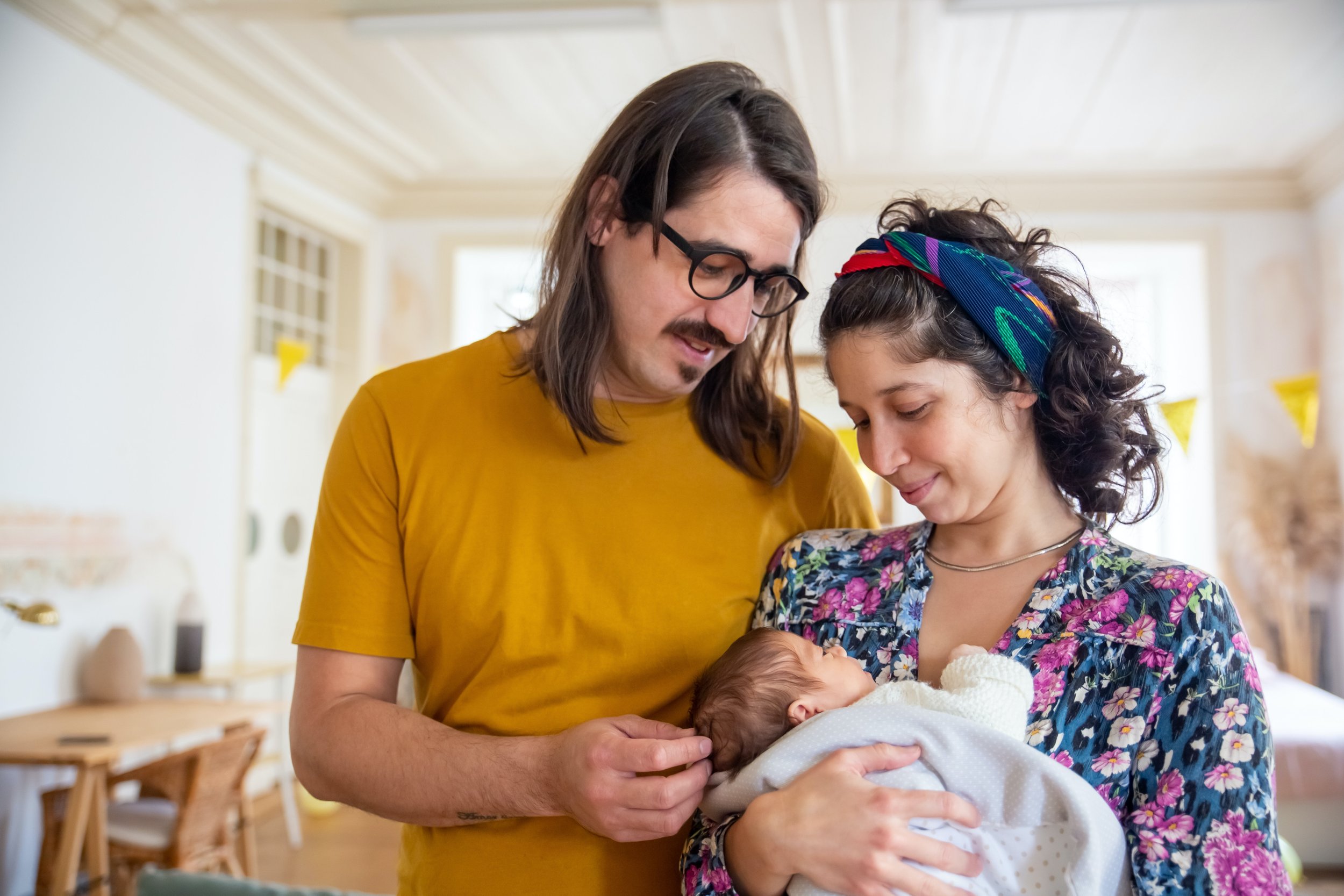 Couple holding their newborn child, smiling at each other.